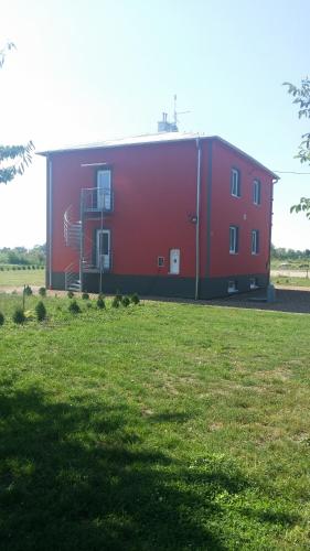 a large red building in a grassy field at Penzion u Janky in Dubňany