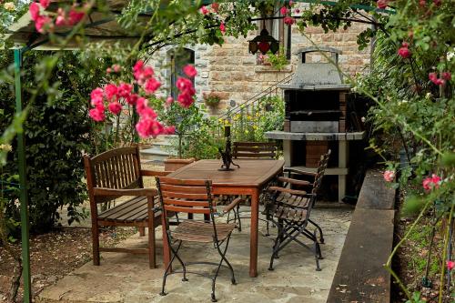 a wooden table and chairs in a garden with pink flowers at La Loggetta - Apartments in Gaiole in Chianti