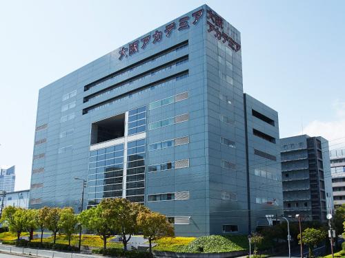 a tall glass building with a sign on it at Osaka Academia in Osaka