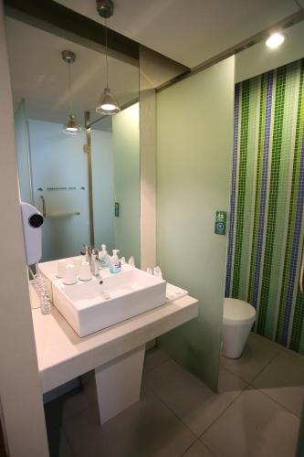 ein Badezimmer mit einem Waschbecken, einem WC und einem Spiegel in der Unterkunft Landscape Fashion Hotel Guangzhou East Station in Guangzhou