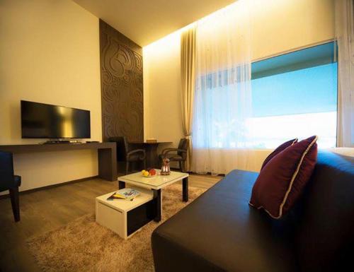 a living room with a couch and a tv at The Beverly Hills Hotel in Nakhon Ratchasima