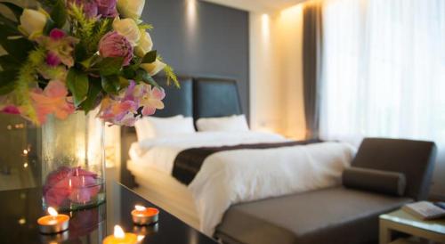 a bedroom with a bed and a couch and flowers at The Beverly Hills Hotel in Nakhon Ratchasima