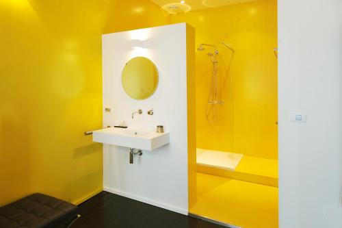 a yellow bathroom with a sink and a shower at B&B Kava in Antwerp