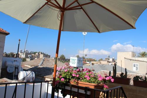 a table with an umbrella and flowers on a balcony at Pedieos Guest House in Lefkosa Turk