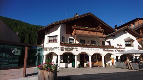 un grande edificio bianco con fiori sulla facciata di Residence Ploner a San Cassiano