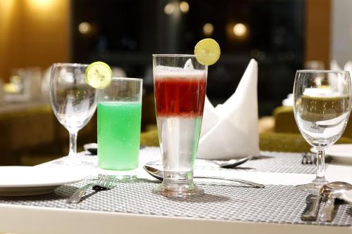 a table with three glasses of different colored drinks at Hotel Silver Heights in Ahmedabad