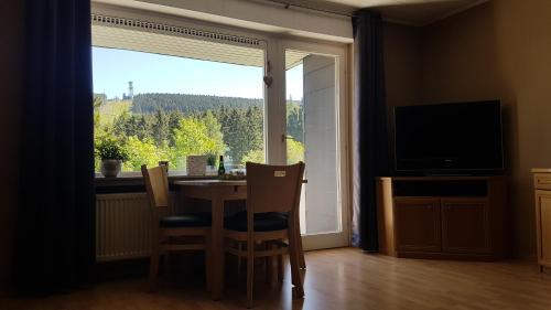 ゴスラーにあるFerienwohnung Singer Am Erlebnisbocksbergのダイニングルーム(テーブル、椅子付)、大きな窓が備わります。