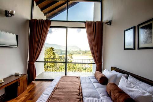 a bedroom with a bed and a large window at The Bungalow in Nuwara Eliya