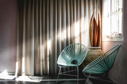 two green chairs sitting in front of a window at Nikis Village in Poros