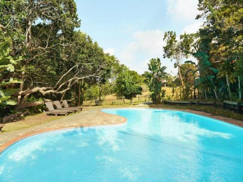 a large blue swimming pool with a bench and trees at Sodwanabay Lodge House 58 in Sodwana Bay