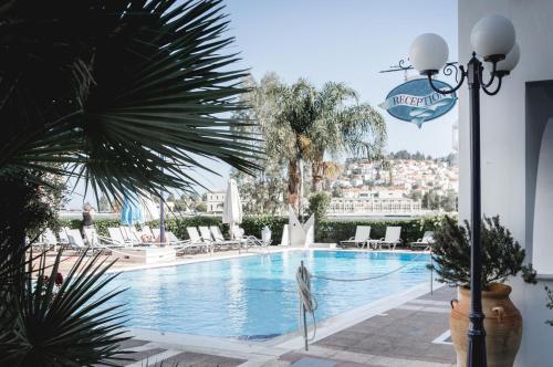a swimming pool with chairs and a palm tree at Nikis Village in Poros