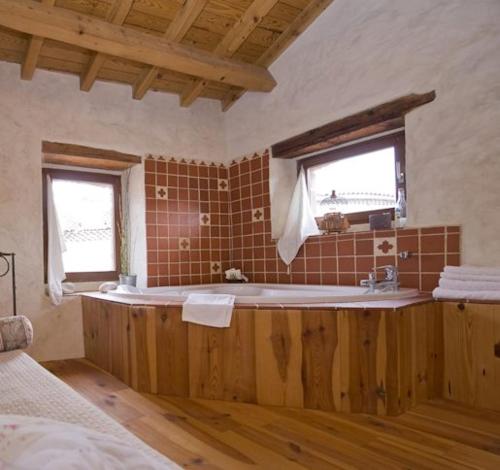 a bathroom with a tub and a sink and two windows at Chez l'Autre in Chilhac