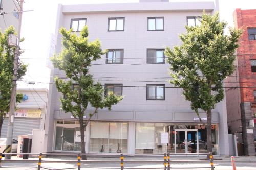 a white building with trees in front of it at Wood House Hotel in Busan