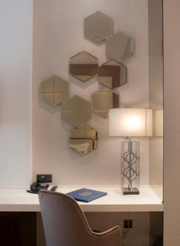 a desk with a chair and a lamp on a wall at Hotel Riva by Aycon in Petrovac na Moru
