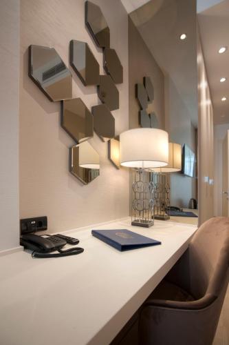 a room with a desk with a phone and a lamp at Hotel Riva by Aycon in Petrovac na Moru