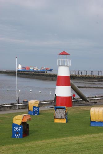 a red and white lighthouse sitting next to the water at Hotel Beckröge in Cuxhaven