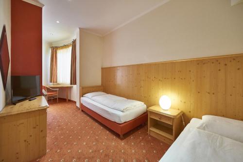 a hotel room with two beds and a television at AlpenOase Sonnhof in Saalbach Hinterglemm