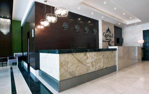 a lobby with a marble counter and chandeliers at Qafqaz Baku City Hotel & Residences in Baku