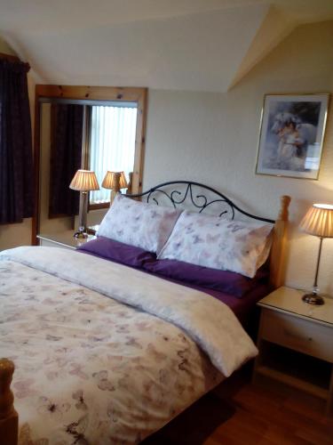 a bedroom with a large bed and two lamps at Melrose in Fort William
