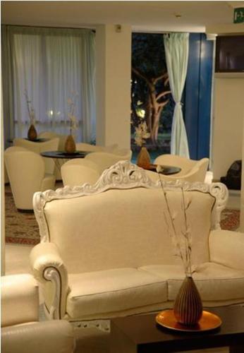 Una sala de estar con un sofá blanco y sillas. en Hotel Aristeo, en Rímini