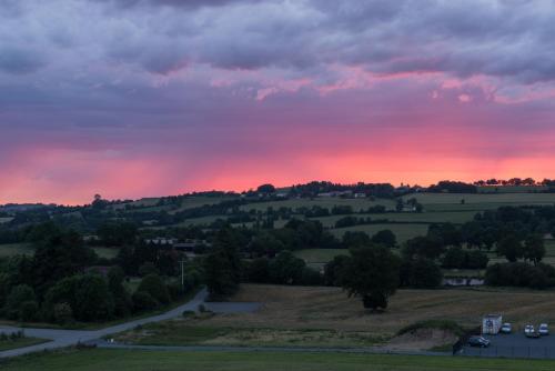 a sunset over the rolling hills of the countryside at Hôtel Omnubo Collection in Les Épesses