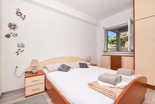 una camera da letto con un letto bianco e una finestra di Apartmani Nina & Mili a Igrane