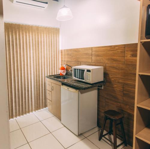 a kitchen with a microwave on a counter at Pousada Bronzatto in Garopaba