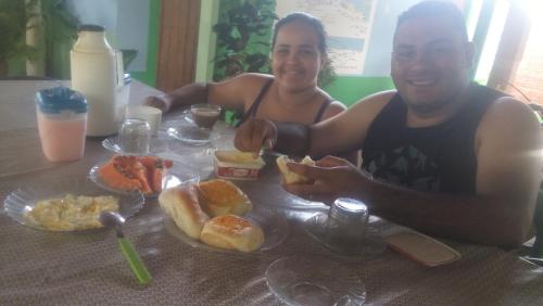 un homme et une femme assis à une table avec de la nourriture dans l'établissement hospedaria pingo de ouro, à Atins
