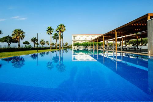 Una gran piscina con palmeras y un edificio. en Estival ElDorado Resort, en Cambrils