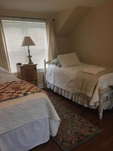 a bedroom with two beds and a window at Stephen Clay Homestead Bed and Breakfast in Candia
