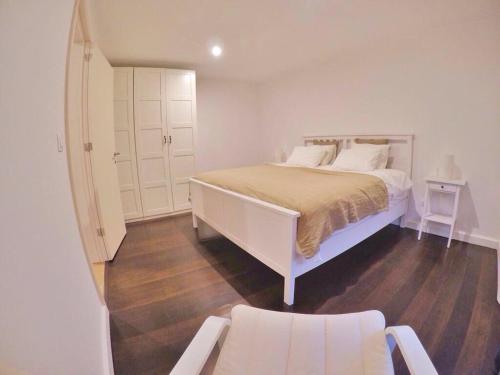 a white bedroom with a bed and a chair at Casa da Batalha in Ponta Delgada