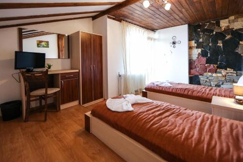 a bedroom with two beds and a desk and a television at House of Time in Ognyanovo