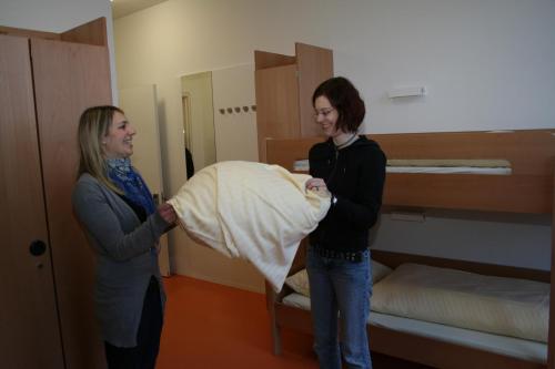 two women standing in a room with a bed at Jugendherberge Stuttgart Neckarpark in Stuttgart