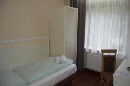 a bedroom with a bed and a cabinet and a window at G&H Hotel Rosengarten in Rosengarten