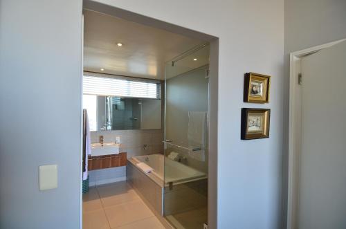a bathroom with a tub and a sink and a mirror at 410 Harbour Bridge in Cape Town