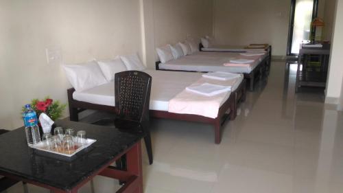 a room with four beds and a table and a counter at Skyrock Inn in Kattappana