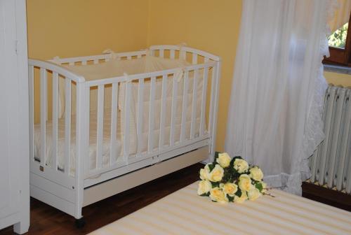 ein weißes Kinderbett mit einem Blumenstrauß in einem Zimmer in der Unterkunft Il gelsomino del Perugino in Città della Pieve