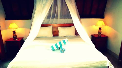 a bedroom with a canopy bed with two lamps at Saeri Matahari Bungalow in Gili Air