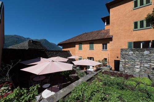 a patio with tables and umbrellas in front of a building at Osteria Locanda Brack in Gudo