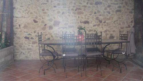 een tafel en stoelen in een kamer met een stenen muur bij La Grange d'Antan in Cruzy