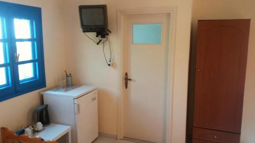 a room with a refrigerator and a tv on the wall at Mouragio Studios in Tyros