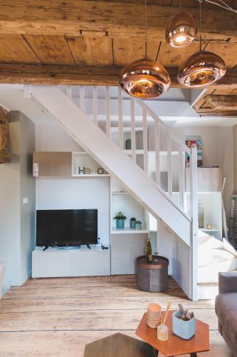 a living room with a tv and a staircase at HISSLA ALSACE CHIC& COSY BARR Wine Route in Barr