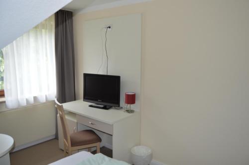 a room with a desk with a television on it at G&H Hotel Rosengarten in Rosengarten