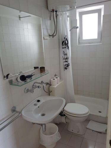 a white bathroom with a toilet and a sink at Apartments Antonio in Tisno