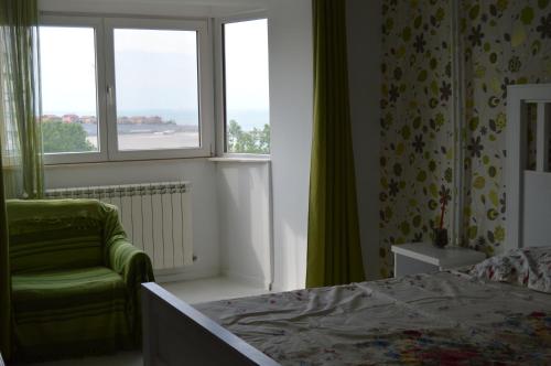 - une chambre avec un lit, une chaise et des fenêtres dans l'établissement Apartament Faleza Nord, à Constanţa