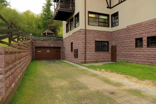 a brick house with a garage and a driveway at Boutique Hotel Sudetia - Medical & SPA in Świeradów-Zdrój