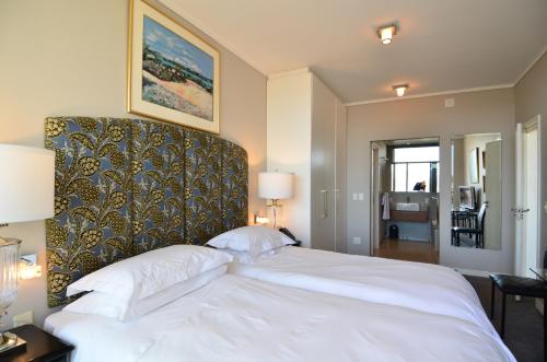 ein Schlafzimmer mit einem großen weißen Bett mit einem großen Kopfteil in der Unterkunft 214 Harbour Bridge in Kapstadt