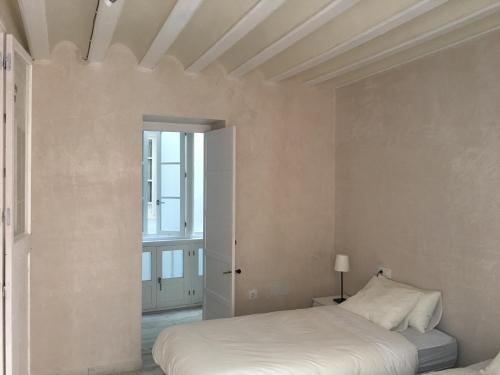 a white bedroom with a bed and a window at Casa Bugambilla Cadiz in Cádiz