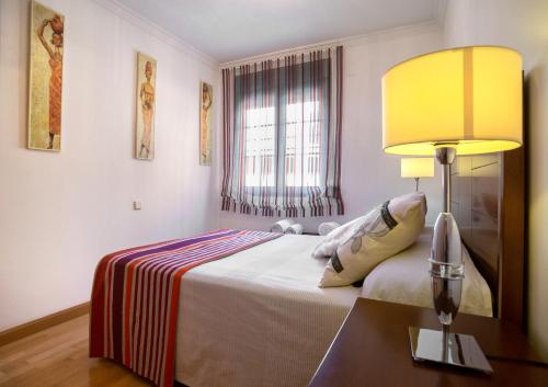 um quarto com uma cama com um candeeiro sobre uma mesa em Apartamento San Juan de los Reyes em Toledo