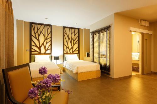 ein Schlafzimmer mit 2 Betten und einem Tisch mit lila Blumen in der Unterkunft Green Point Residence Hotel in Ban Khi Sua